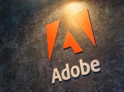 Orangenes Logo von Adobe an einer dunkelgrauen Wand