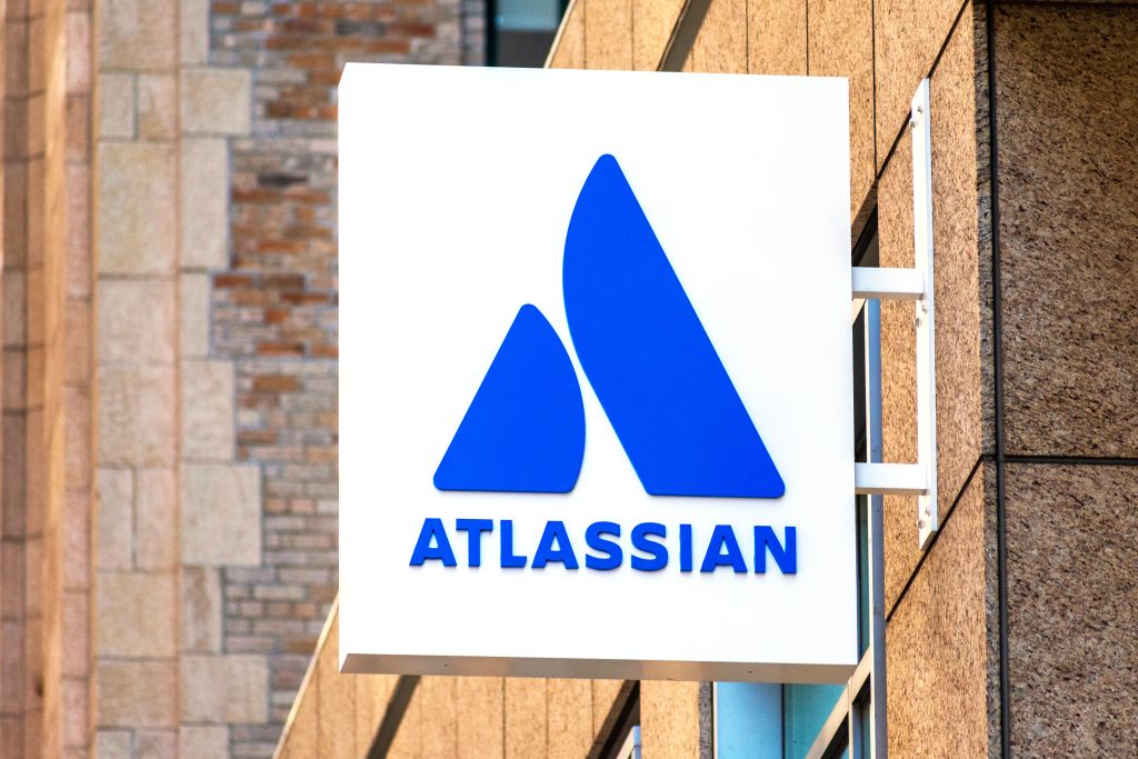 Das Bild zeigt ein Firmenschild mit dem blauen Atlassian-Logo und dem Schriftzug „ATLASSIAN“ an der Außenfassade eines Gebäudes.