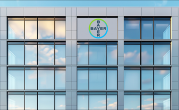 ein modernes Gebäude mit Glasfassade und dem runden Bayer-Logo in der Mitte.
