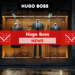eine Schaufensterauslage von HUGO BOSS mit eleganten Herrenanzügen, beleuchtet durch warmes Licht, , mit einem Hugo Boss NEWS Banner