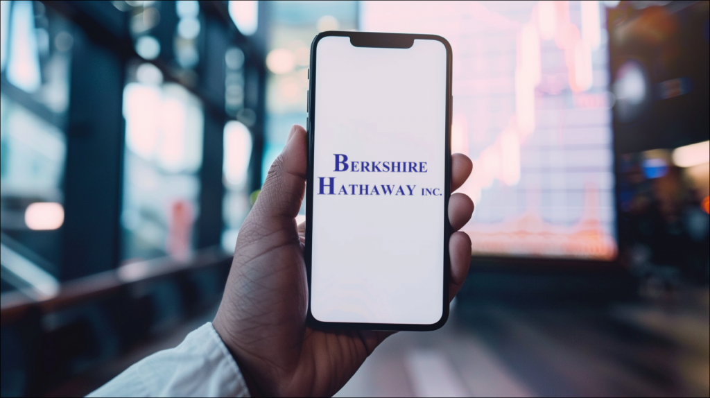 Smartphone mit weißem Bildschirm und Logo in der Hand, Aktienchart im Hintergrund