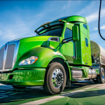 Ein Wasserstoff-Brennstoffzellen-Lastwagen ist an einer grünen Zapfsäule unter strahlend blauem Himmel