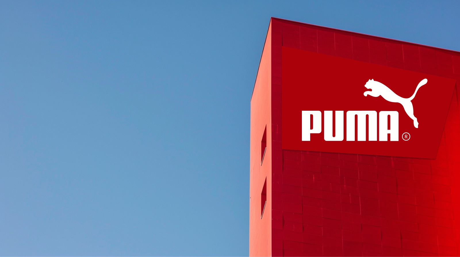 ein großer roter Monolith mit dem Puma-Logo und dem Markennamen in Weiß vor einem klaren blauen Himmel