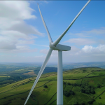 Eine große Windkraftanlage, die vor einem blauen Himmel über einer grünen Landschaft steht, Nahaufnahme
