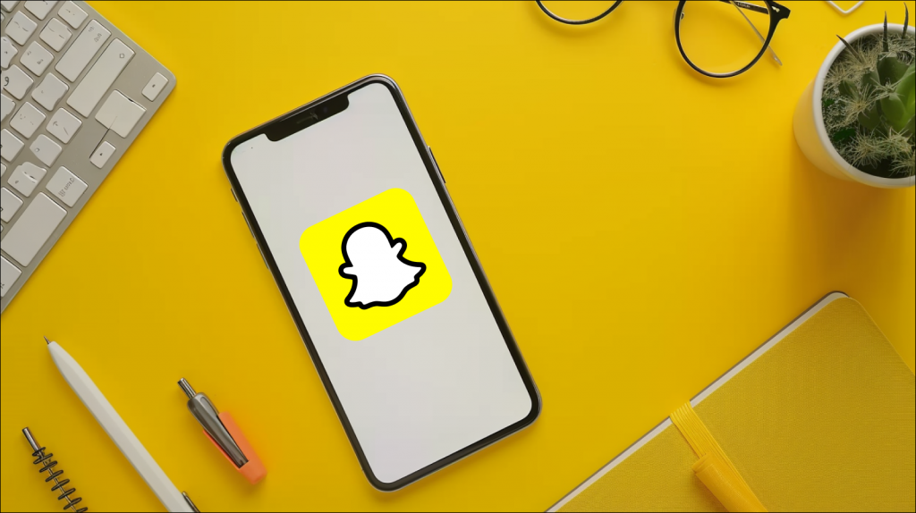 Smartphone mit weißem Bildschirm und Logo liegt auf dem gelben Schreibtisch