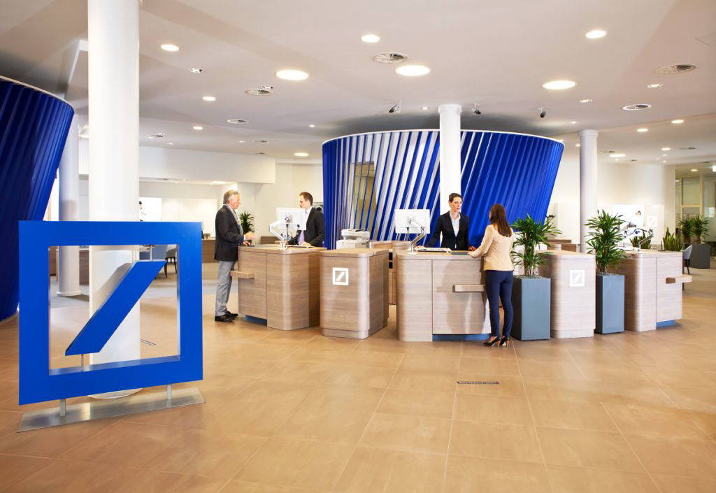 Innenansicht einer modernen Deutsche-Bank-Filiale mit Kundenberatung an offenen Schaltern – Fokus auf persönlichen Service. © Deutsche Bank AG