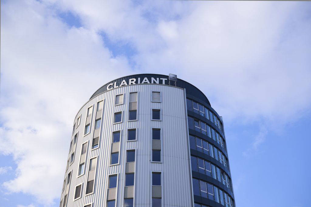 Moderner Gebäudeturm mit Clariant-Schriftzug auf dem Dach, aufgenommen aus leichter Untersicht bei leicht bewölktem Himmel.