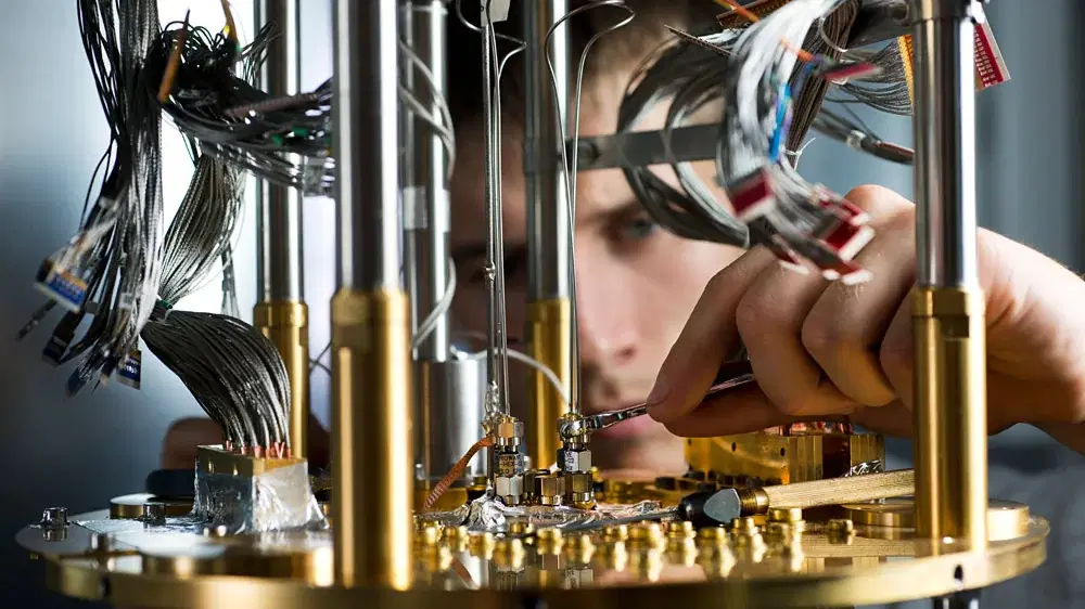 Ein Techniker arbeitet konzentriert an der filigranen Verkabelung eines Quantencomputers im Labor von D-Wave.
