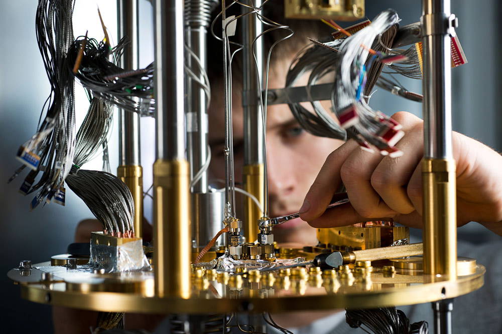 Ein Techniker arbeitet konzentriert an der filigranen Verkabelung eines Quantencomputers im Labor von D-Wave.