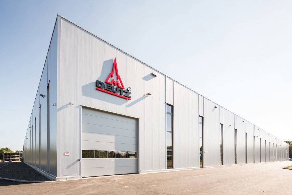 Außenansicht einer modernen Produktionshalle der Deutz AG mit Firmenlogo an der Fassade, Tageslichtaufnahme bei klarem Himmel