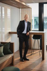 Marc Bürki, CEO von Swissquote, steht in einem modernen, lichtdurchfluteten Büro mit Holzelementen und Ausblick auf den Firmencampus.