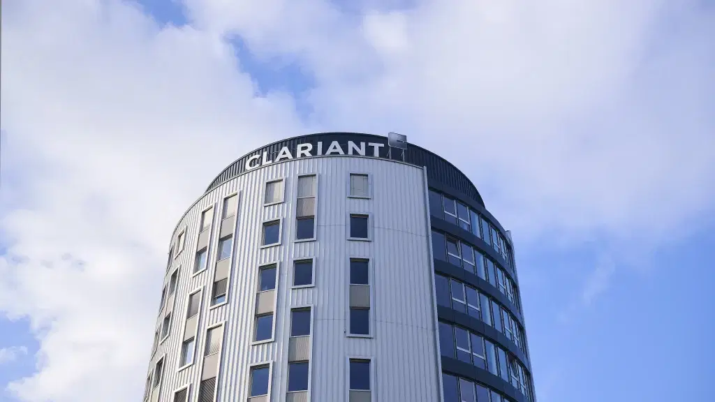 Moderner Gebäudeturm mit Clariant-Schriftzug auf dem Dach, aufgenommen aus leichter Untersicht bei leicht bewölktem Himmel.