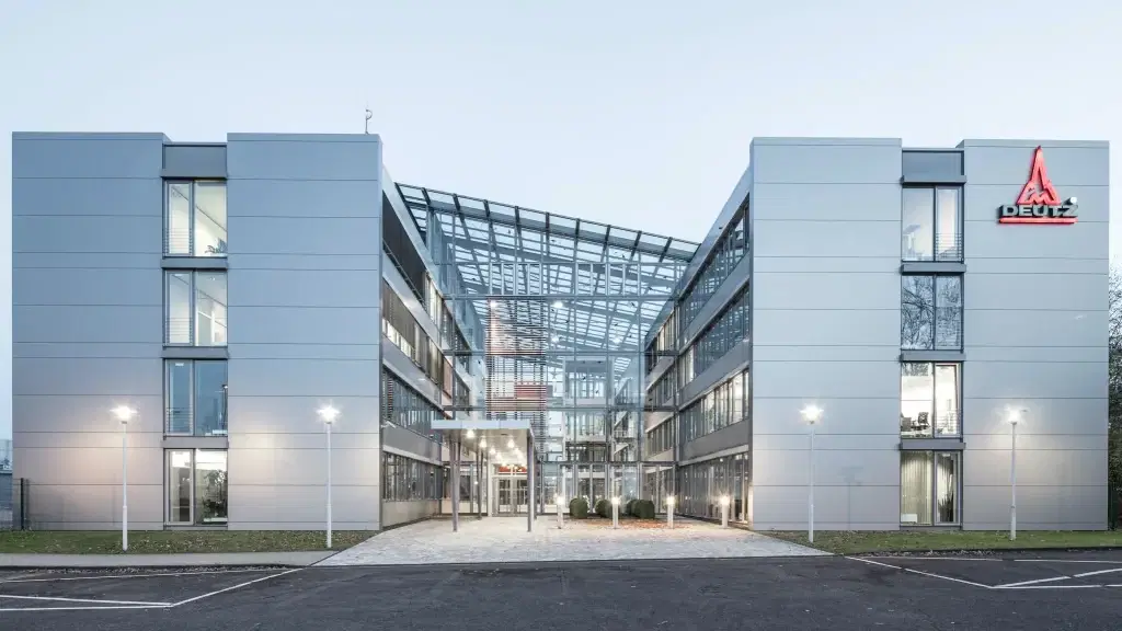 Hauptverwaltung der Deutz AG in Köln mit Glasdach und moderner Architektur, frontal fotografiert bei Dämmerung