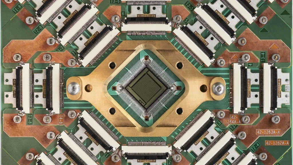 Nahaufnahme eines komplexen Quantenchips von D-Wave mit zahlreichen Steckverbindungen und einem zentralen Prozessor.