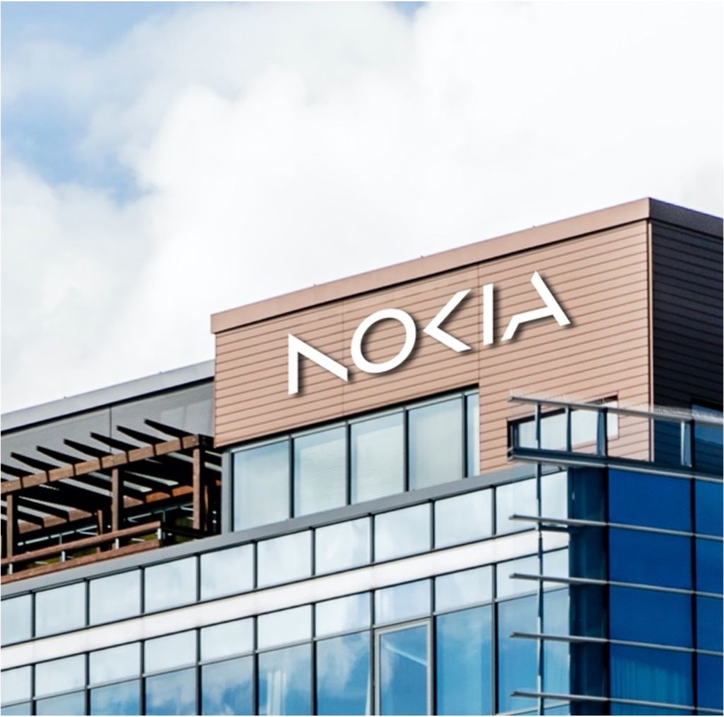 Gebäude mit moderner Glasfassade und großem Nokia-Logo auf der Fassade unter blauem Himmel.