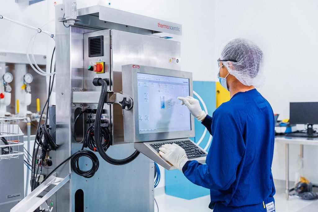 Thermo Fisher-Aktie: Geht da noch mehr? Ein Labormitarbeiter in Schutzkleidung bedient ein modernes Analysegerät von Thermo Fisher Scientific über einen großen Touchscreen in einem sterilen Laborumfeld.