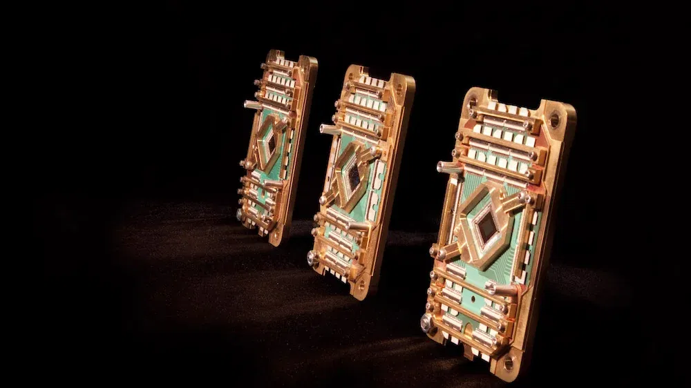 D-Wave Quantum: Gipfel – Aus und vorbei Drei goldene D-Wave-Quantenprozessoren aufgereiht auf schwarzem Untergrund, futuristisch beleuchtet.