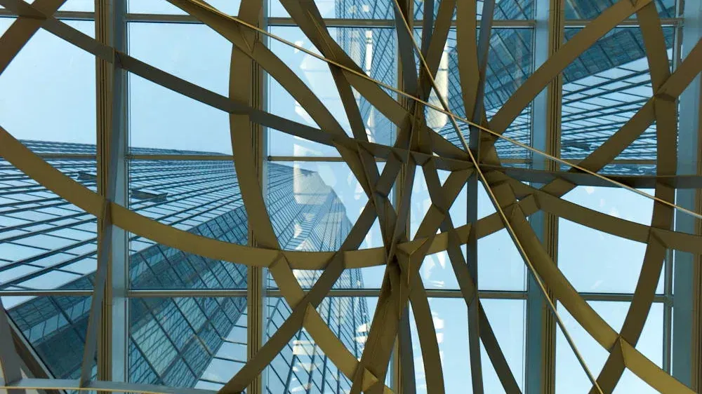 Blick durch ein künstlerisch gestaltetes Deckenelement auf die Glasfassade des Deutsche-Bank-Hochhauses in Frankfurt/Main – modernes Design und Transparenz.