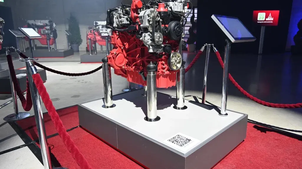 DEUTZ TCD 3.9 Motor ausgestellt auf rotem Podest, mit Info-Terminal und Absperrungen, Messeumgebung mit weiteren Motoren im Hintergrund